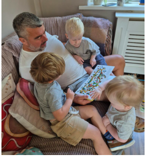 Father reading a book to his three children.